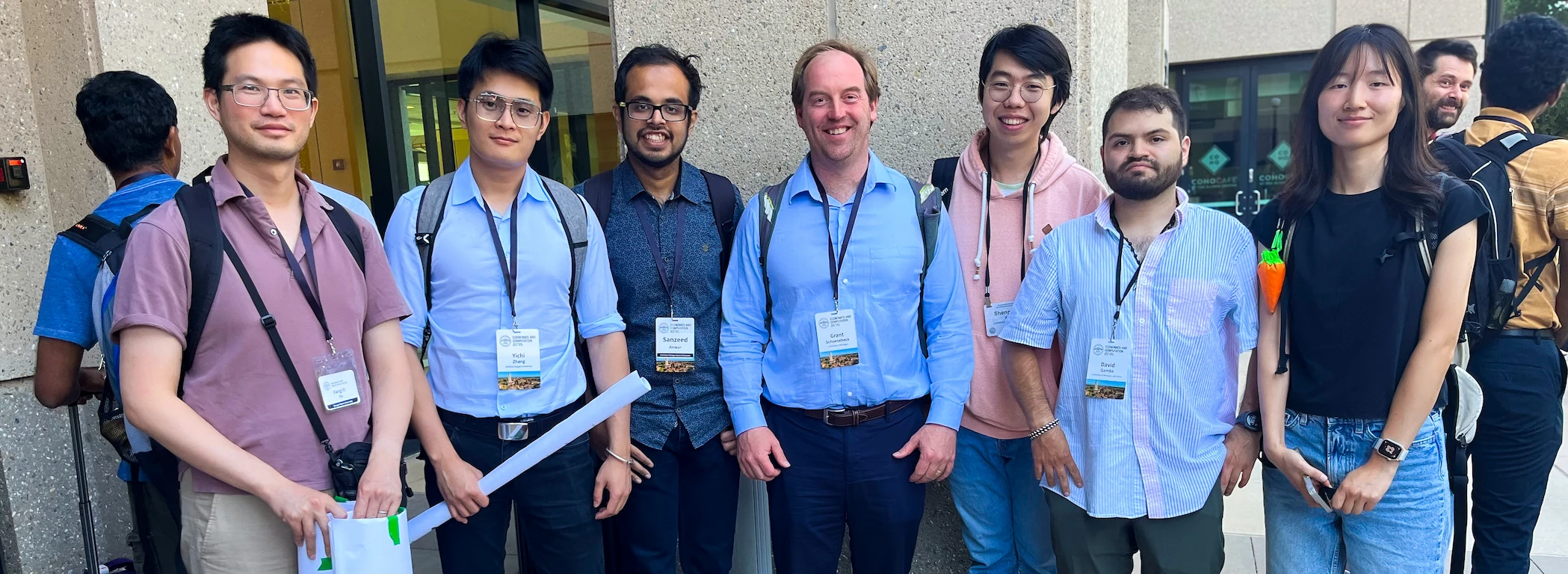 UTIL lab members standing together outside a conference venue, wearing conference name badges